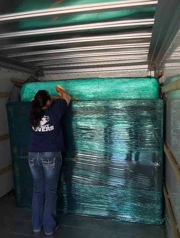 Movers near me using straps and padding to secure furniture inside a moving truck for safe transport